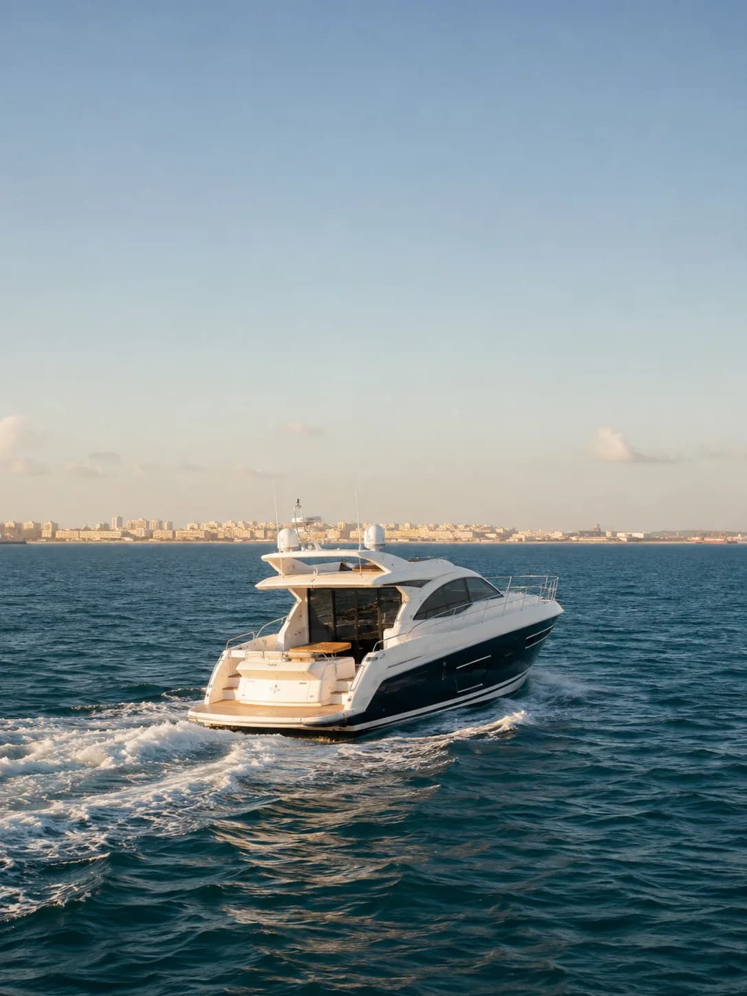 Yate blanco navegando por la Bahía de Cádiz con la ciudad al fondo
