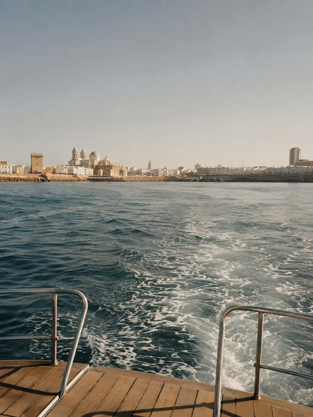 Vista de Cádiz alejándose desde la cubierta de una embarcación