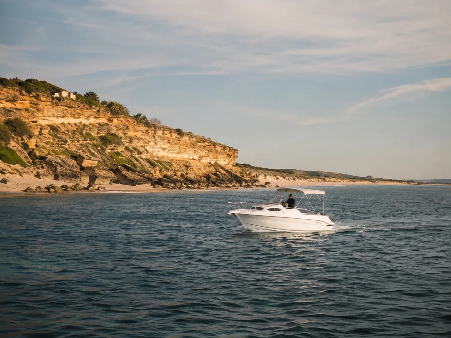 Barco navegando frente a las playas, calas y acantilados bajos de Conil