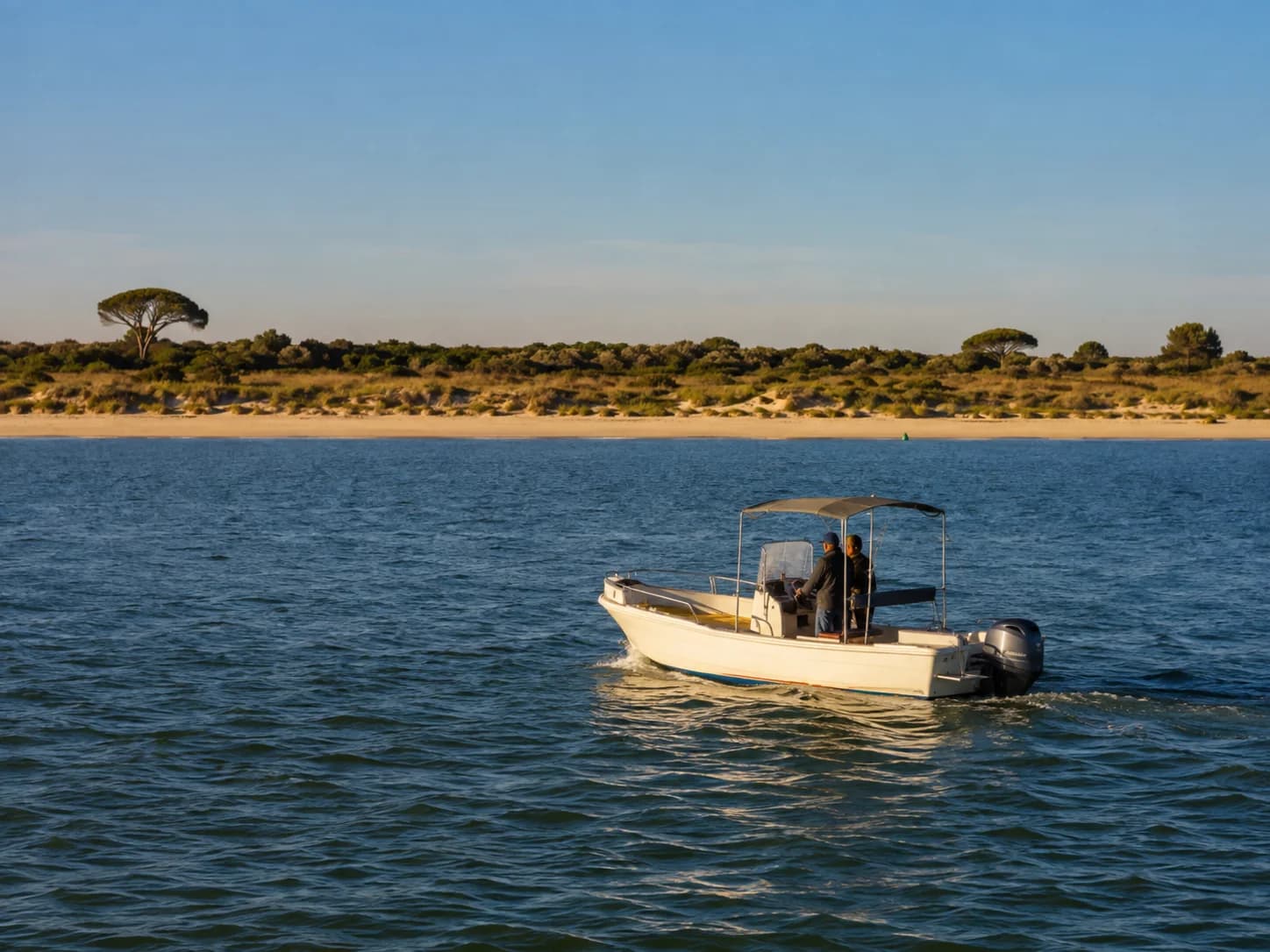 Embarcación navegando en la desembocadura del Guadalquivir frente a la orilla de Doñana